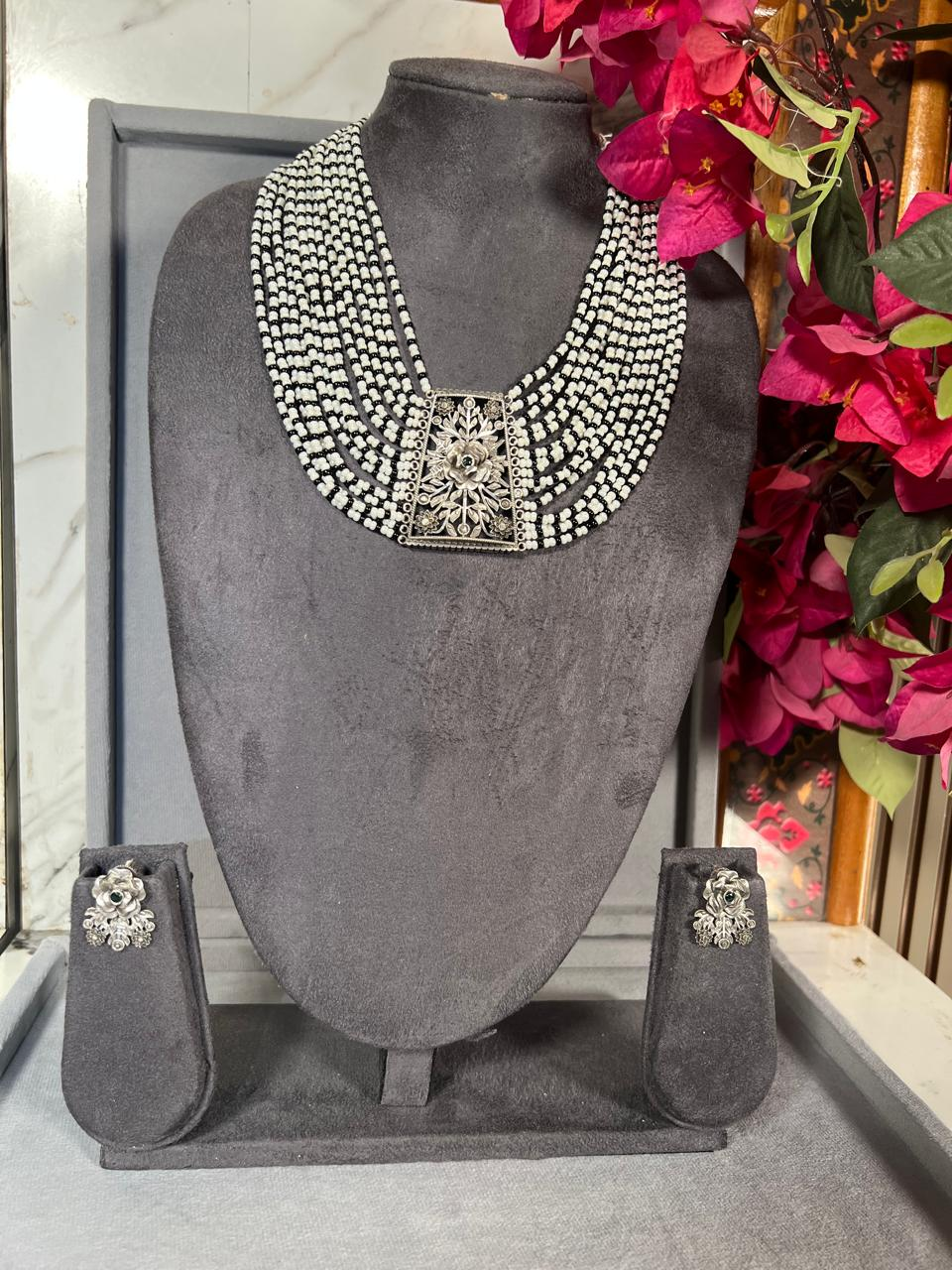 Black-and-white multi-strand beaded necklace set with oxidised floral centrepiece and matching earrings